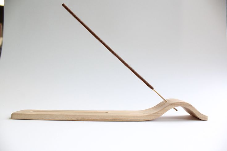 a wooden object with a long stick sticking out of it's end on a white surface