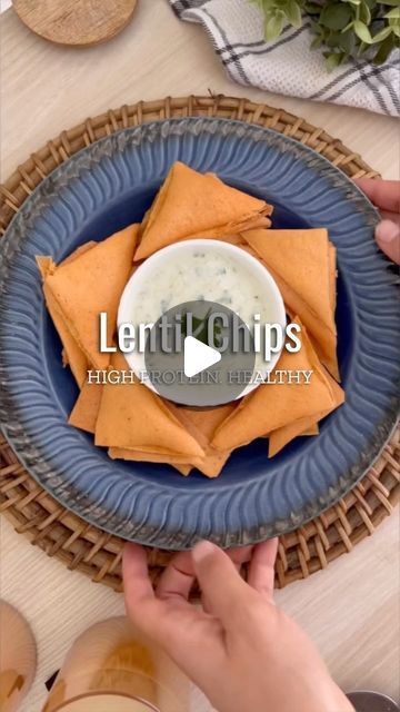 a blue plate topped with tortilla chips next to a bowl of dip sauce