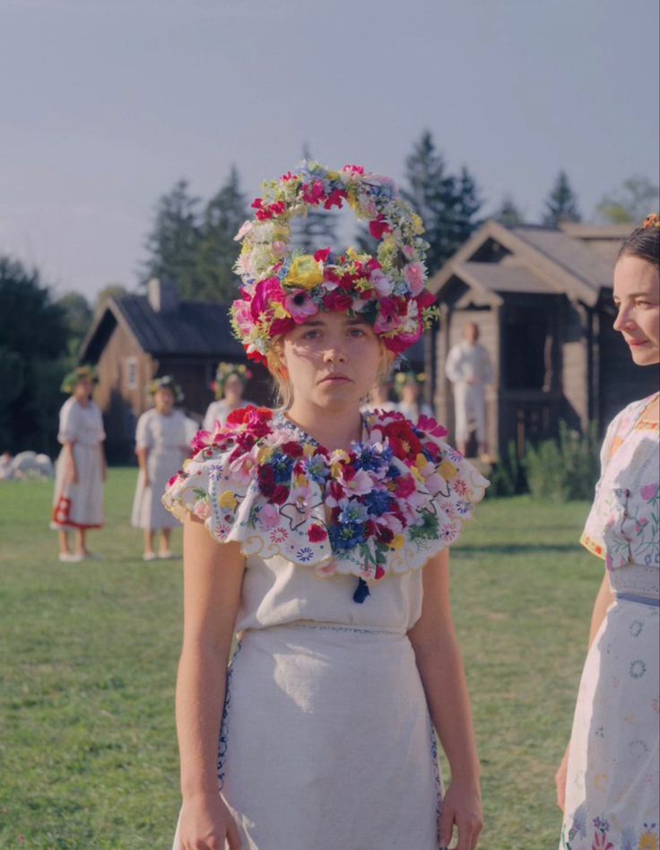 two women in white dresses standing next to each other with flowers on their head and neck