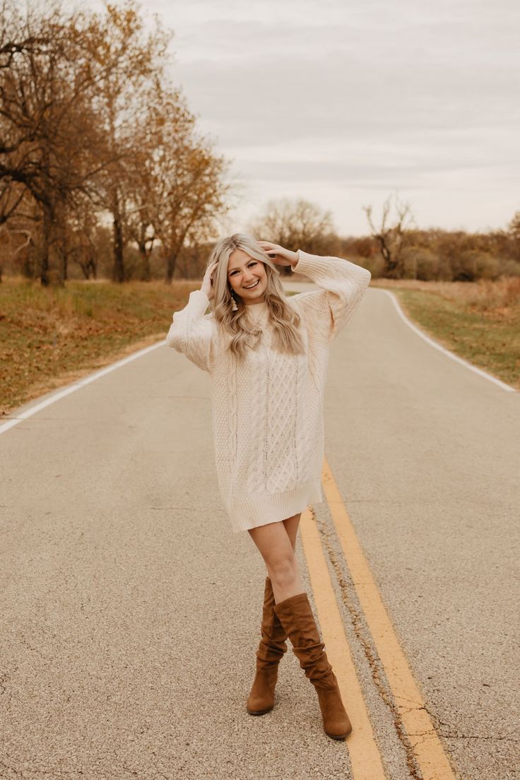 a woman standing in the middle of an empty road with her hands on her head