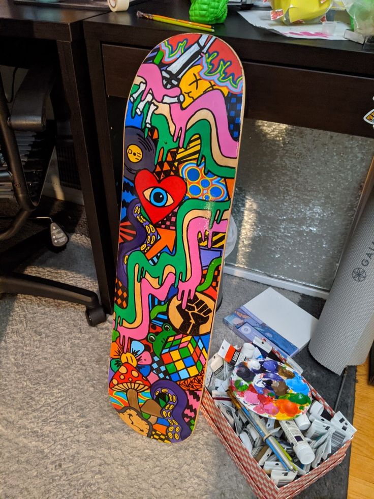 a colorful skateboard sitting on the floor next to a desk