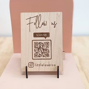 a wooden card holder with a qr code on it that says follow us scan me