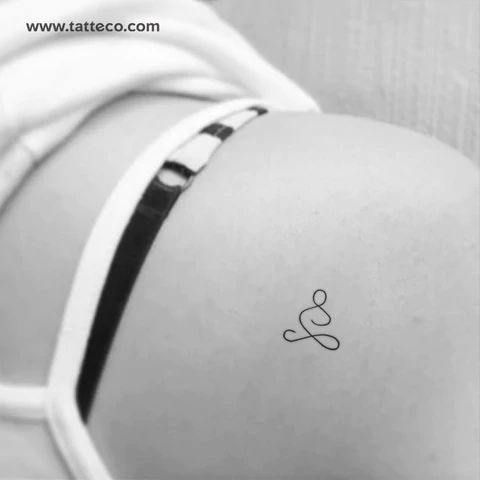 the back of a woman's stomach with a small tattoo on her left side