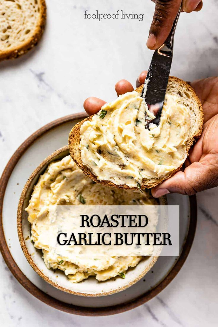 a person holding a knife over a bowl of food with the words roasted garlic butter on it