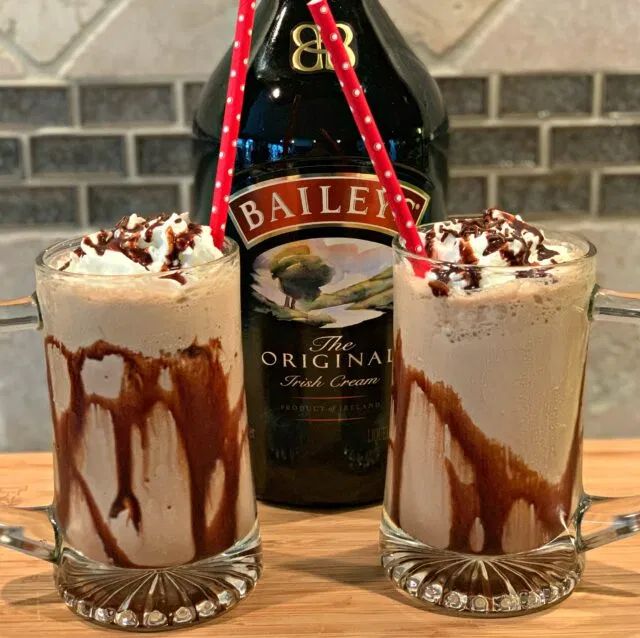 two glasses filled with ice cream next to a bottle of bailey's irish cream