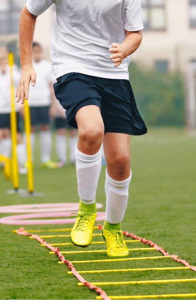 a young man is running on a track made out of yellow and white sticks with his feet in the air