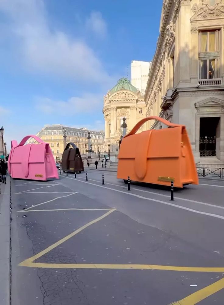 an orange and pink car sitting in the middle of a street