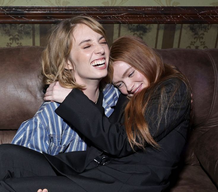 two young women hugging each other while sitting on a couch