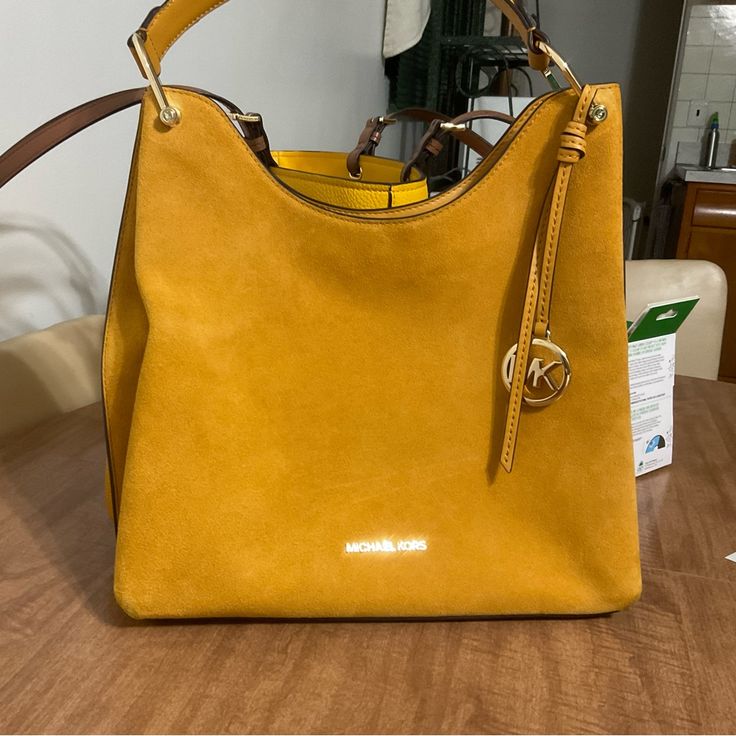 Joan Purse In Mustard (Merigold) Color. The Sides On The Suede Side Do Have Signs Of Wear ( Not Sure If Dirt Or Just Wear) I Did Try To Show In Pics. The Other Side Is Pebble Leather. It Has A Snap Closure, One Zippered Pocket On The Inside, And Two More Inside Pockets On The Other Side. The Measurements Are L 12 1/4” X W 5” X H 9 3/4”. The Strap Is 7 1/4”. All Measurements Are Approx. Gold Top Handle Shoulder Bag For Errands, Gold Top Handle Bag For Errands, Designer Gold Hobo Shoulder Bag, Gold Shoulder Bag With Branded Hardware And Double Handle, Gold Hobo Bag With Detachable Strap For Shopping, Gold Bag With Detachable Strap For Errands, Gold Bags With Detachable Strap For Errands, Gold Satchel Bag With Branded Hardware, Gold Hobo Bag With Detachable Double Handle