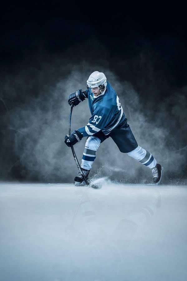 an ice hockey player in blue and white uniform is playing on the ice with his stick