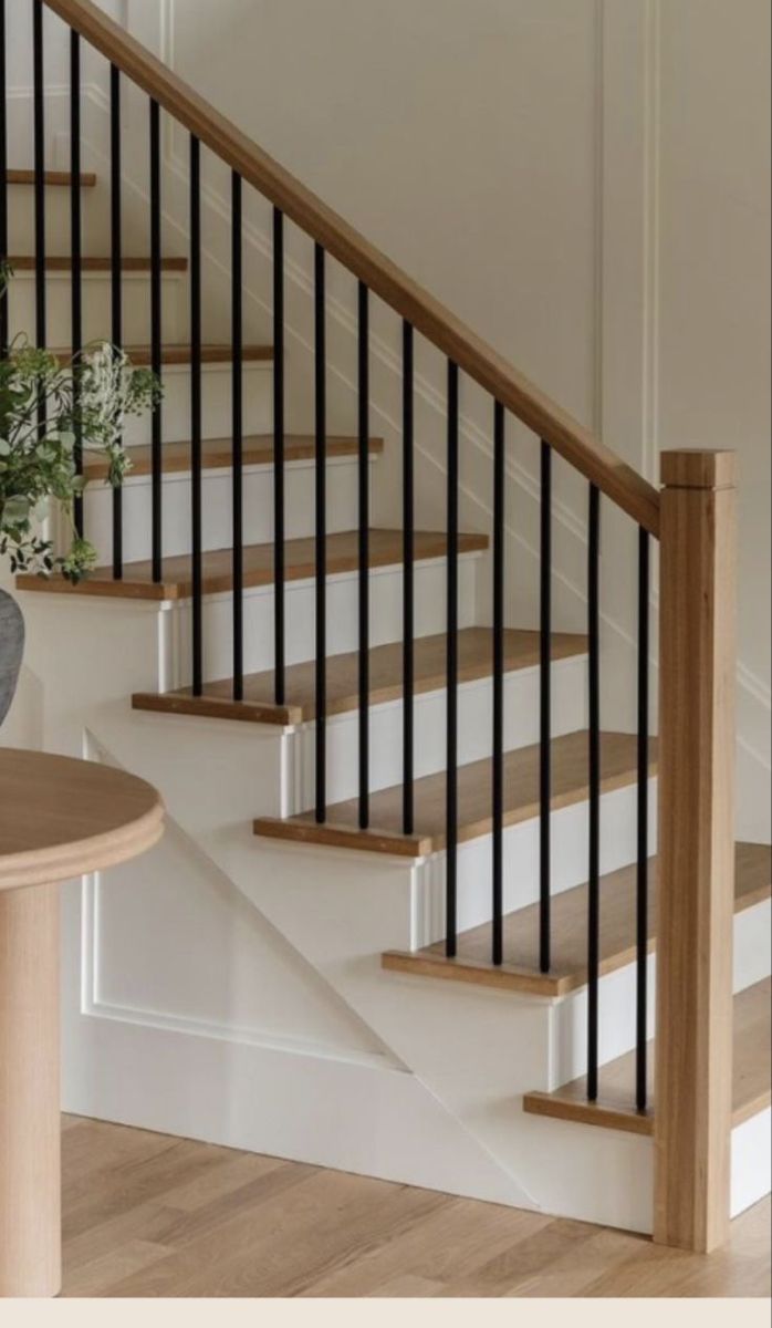 there is a vase with flowers on the table next to the stair case in this house