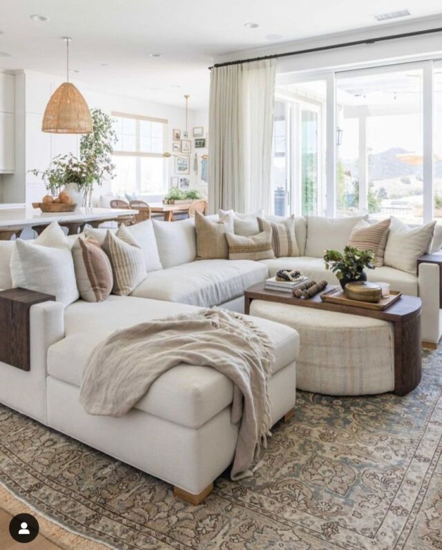 a living room filled with white furniture and lots of pillows on top of it's couches