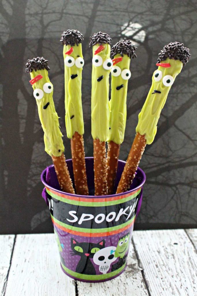 a cup filled with halloween pretzels sitting on top of a table