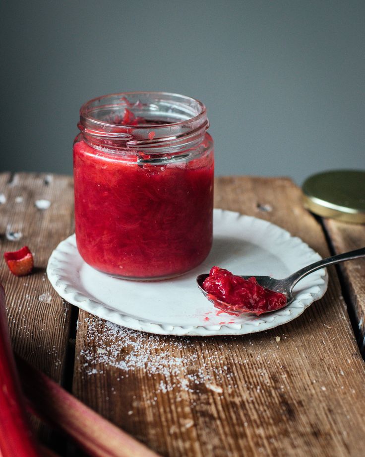 a spoon is sitting on a plate next to a jar filled with red liquid and powdered sugar