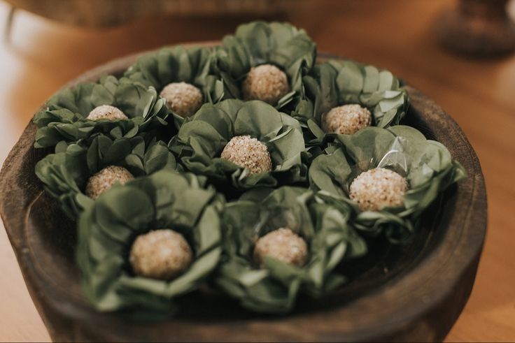 a wooden bowl filled with green flowers on top of a table