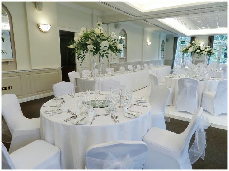 a banquet room set up with white linens and flowers