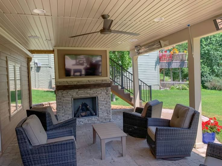 an outdoor living area with wicker furniture and a flat screen tv on the wall