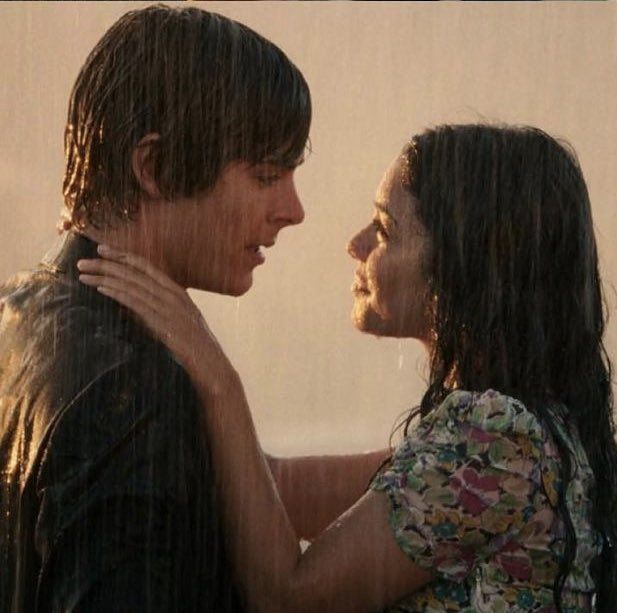 a young man and woman embracing in the rain with their arms around each other as they stare into each others eyes