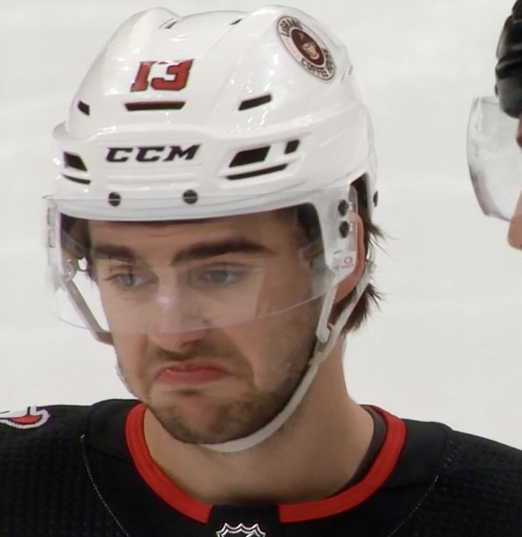 a close up of a hockey player wearing a helmet and looking at the camera with an intense look on his face