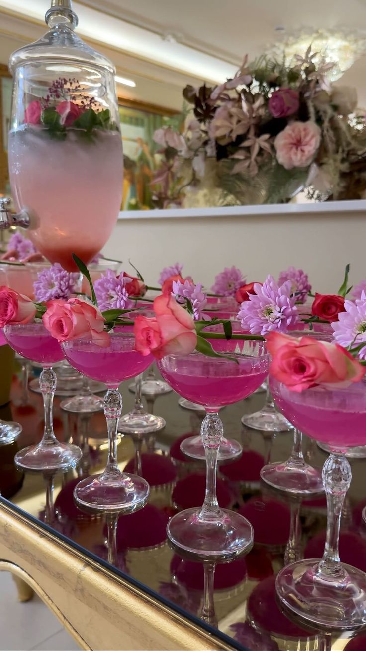 several wine glasses filled with pink liquid and flowers