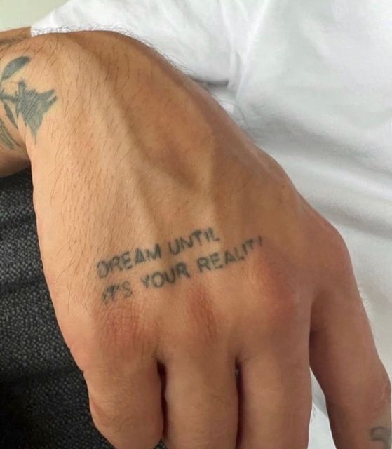 a man with a tattoo on his left hand and the words dream until it's your reality