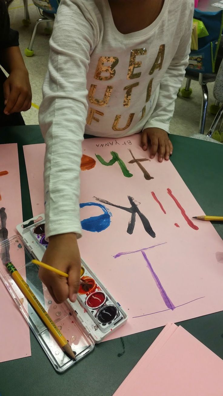 a young child is painting on pink paper