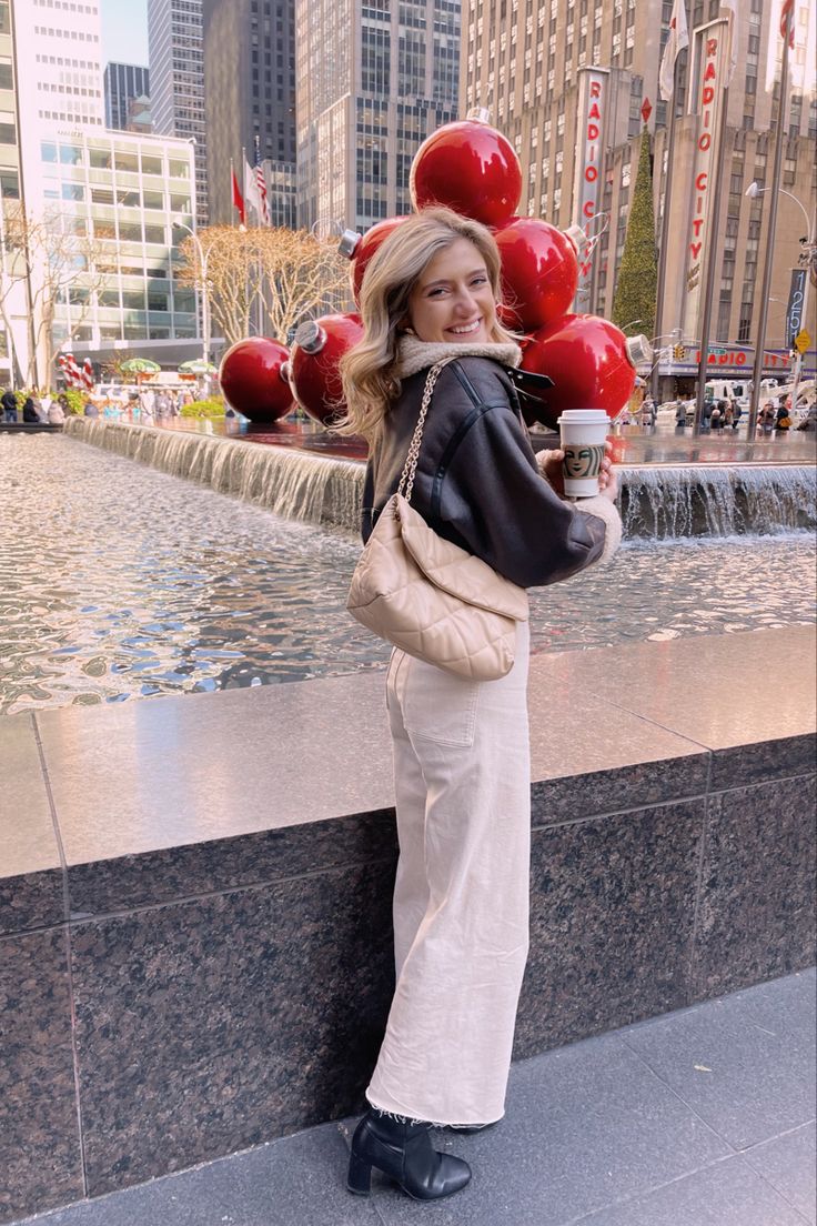 a woman standing in front of a fountain with red balloons