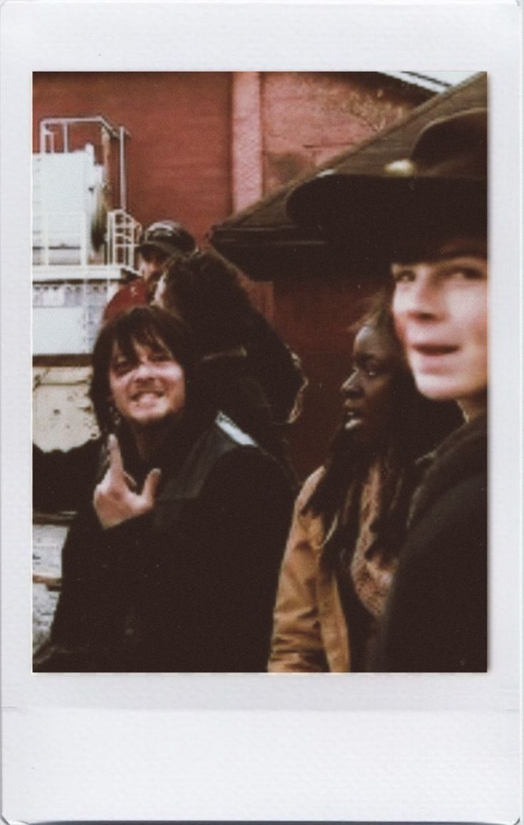 two women standing next to each other in front of a red brick building and one is making the peace sign