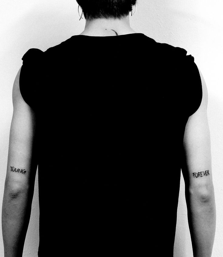 the back of a man's head with tattoos on his left arm and shoulder