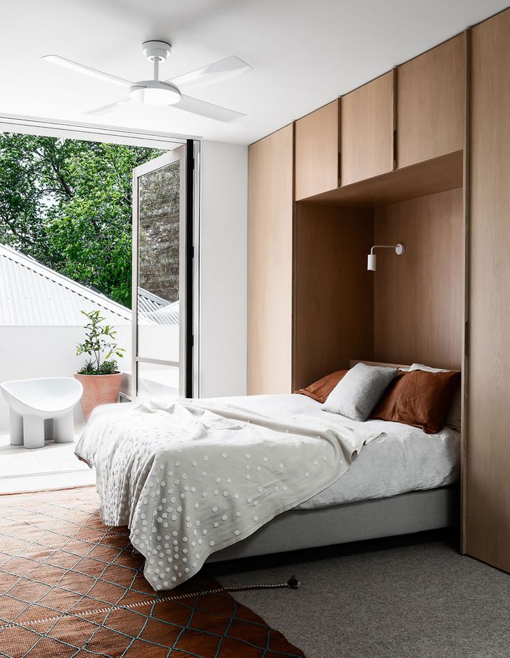 a bed sitting in a bedroom next to a sliding glass door with an open window