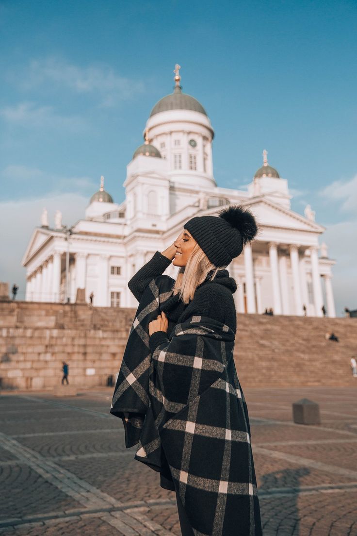 a woman standing in front of a building wearing a black and white checkered coat