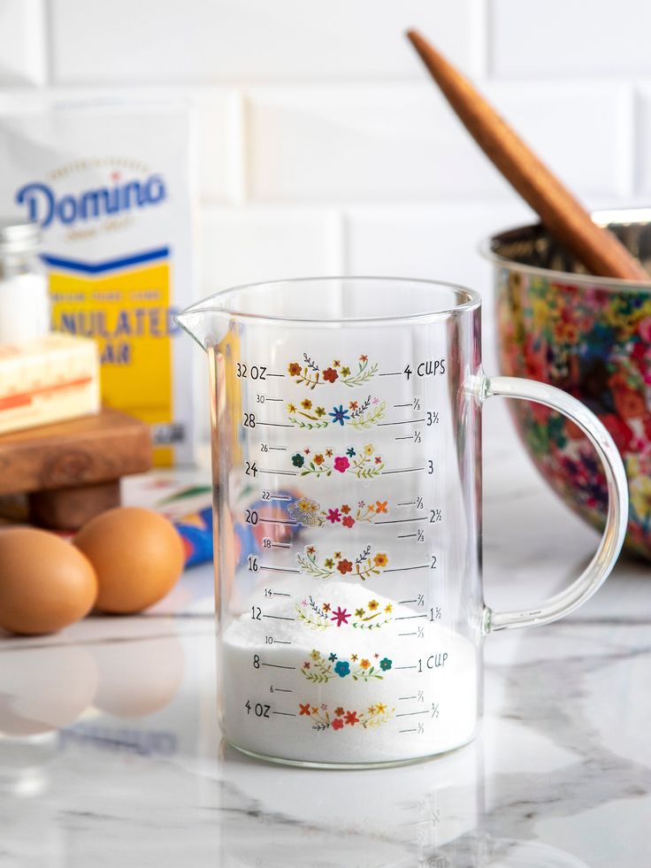 a glass measuring cup sitting on top of a counter next to eggs and other ingredients