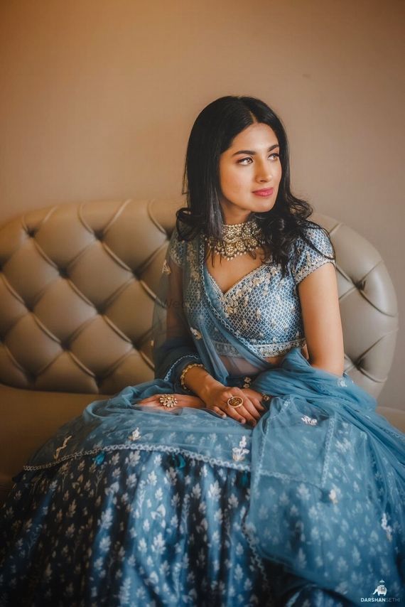 a woman sitting on top of a couch wearing a blue dress