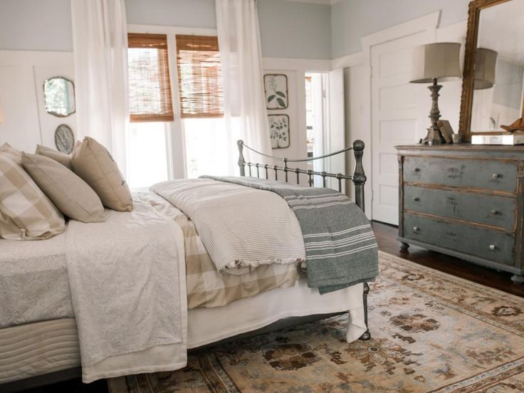 a bedroom with a bed, dresser and mirror on the wall next to an area rug