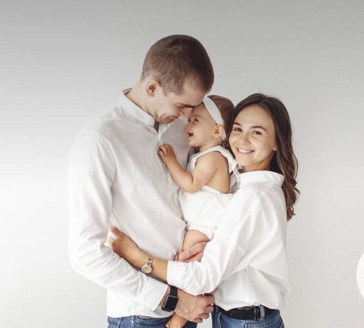 a man and woman holding a baby in their arms while standing next to each other