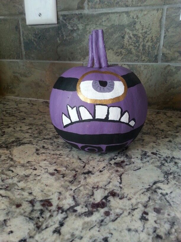 a purple painted pumpkin sitting on top of a counter next to a tile backsplash