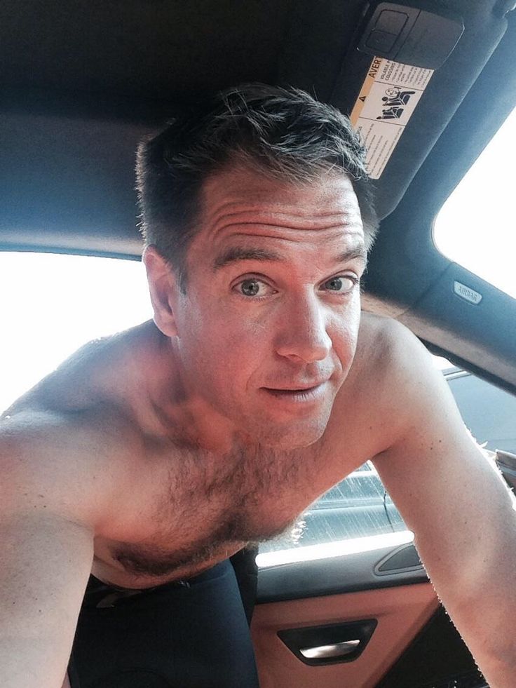 a shirtless man sitting in the back seat of a car looking at the camera