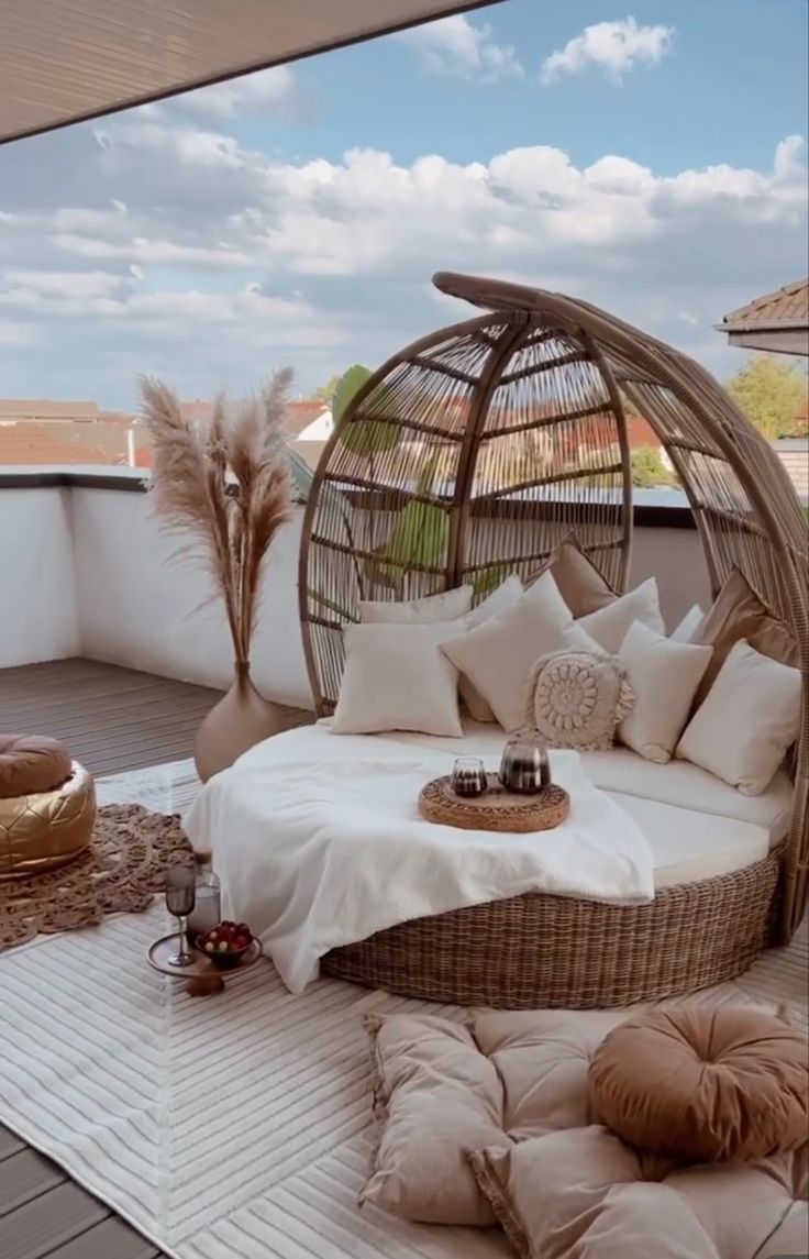 a wicker bed on the roof of a building with lots of pillows and blankets