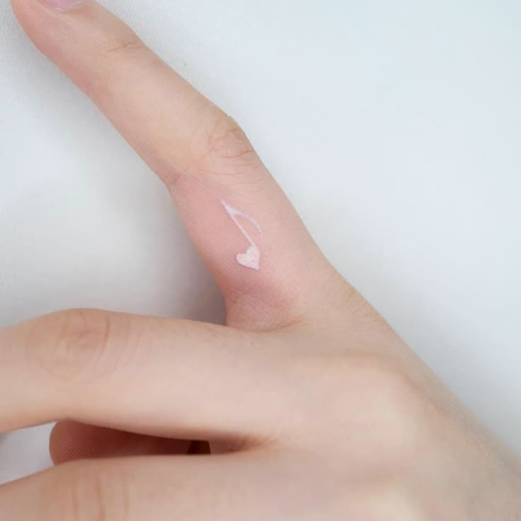 a person's finger with a small white heart painted on the tip of it