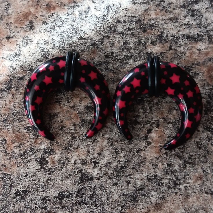 pair of black and red hoop earrings sitting on top of a granite counter next to each other