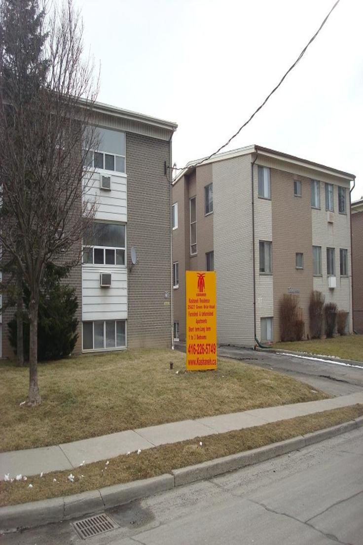 an orange sign sitting on the side of a road in front of two apartment buildings