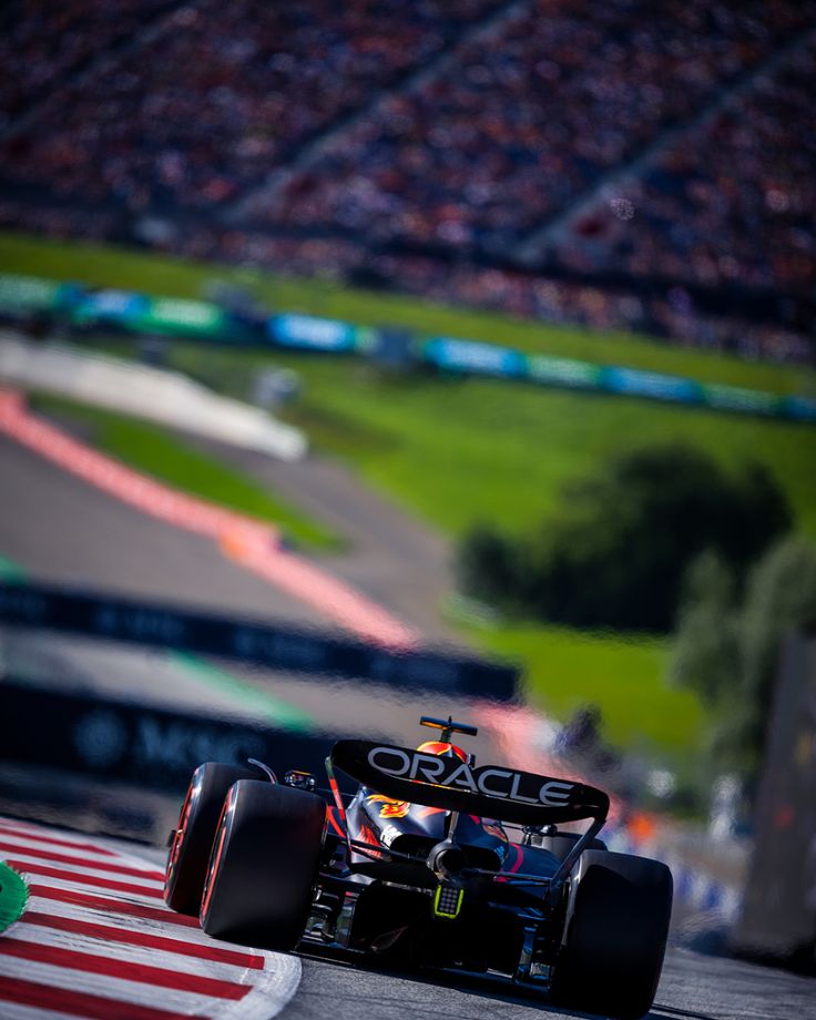 a man driving a race car on top of a track in front of a crowd