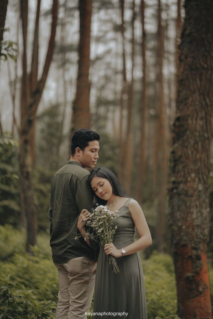 a man and woman are standing in the woods