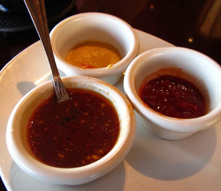 three bowls of sauce on a white plate