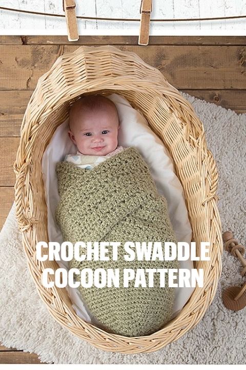 a baby wrapped in a crochet swaddle sits in a wicker basket