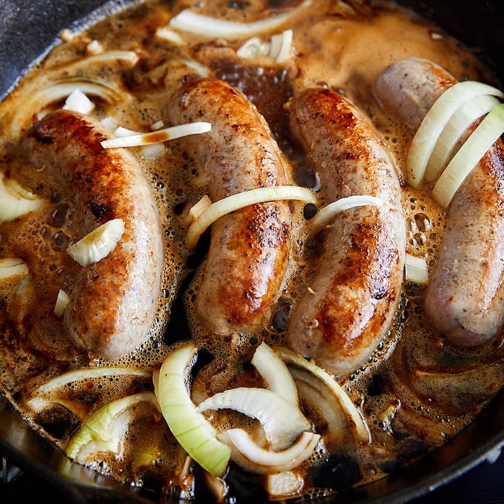 sausages and onions cooking in a skillet