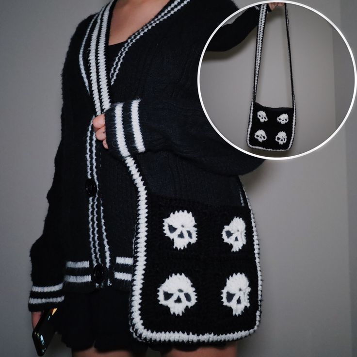 a woman wearing a black and white skull sweater holding a cell phone in her hand