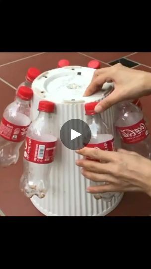 two hands are reaching into a canister filled with water and soda bottles on the floor