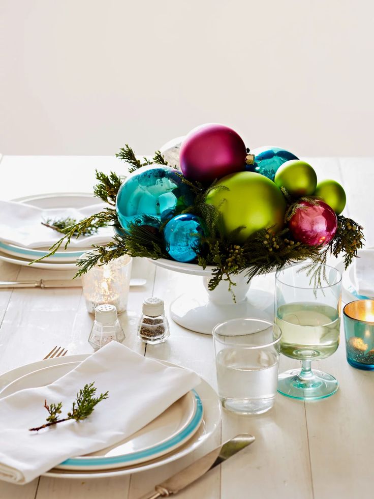 the table is set for christmas dinner with silverware and colorful baubles on it