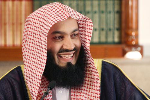 a man with a beard wearing a red and white headdress smiles at the camera